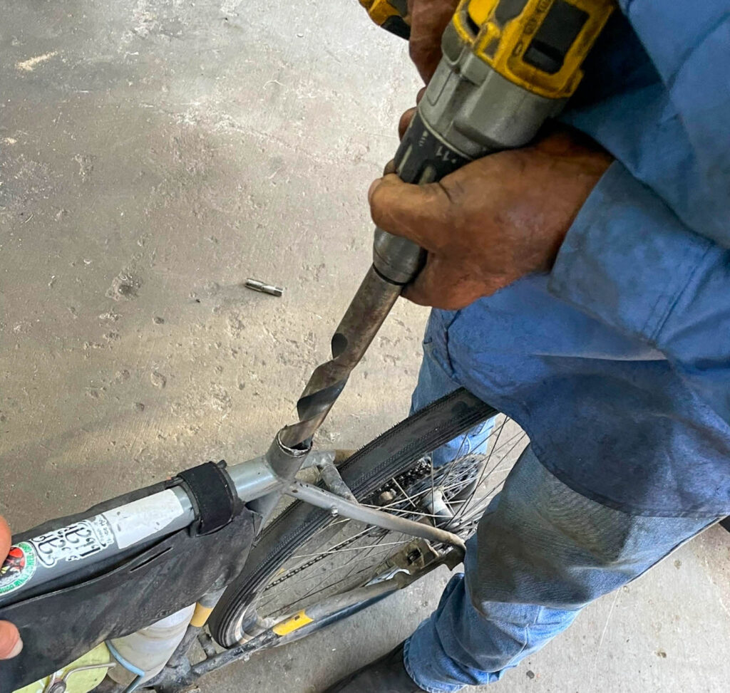 Broken seatpost being drilled out in a workshop during long-distance cycling tour