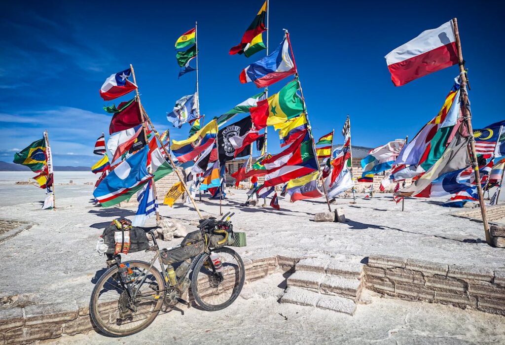 Loaded touring bicycle in front of flags at Salar de Uyuni Bolivia