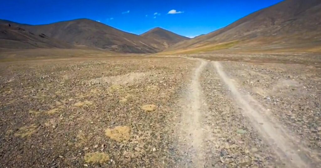 Faint dirt track crossing a wide high-altitude valley on the Zorkul detour, Pamir Highway