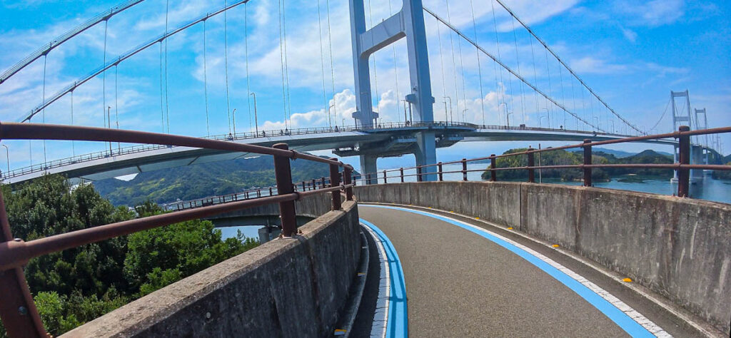 Cycling path curving toward the suspension towers of a Shimanami Kaido bridge over the Seto Inland Sea